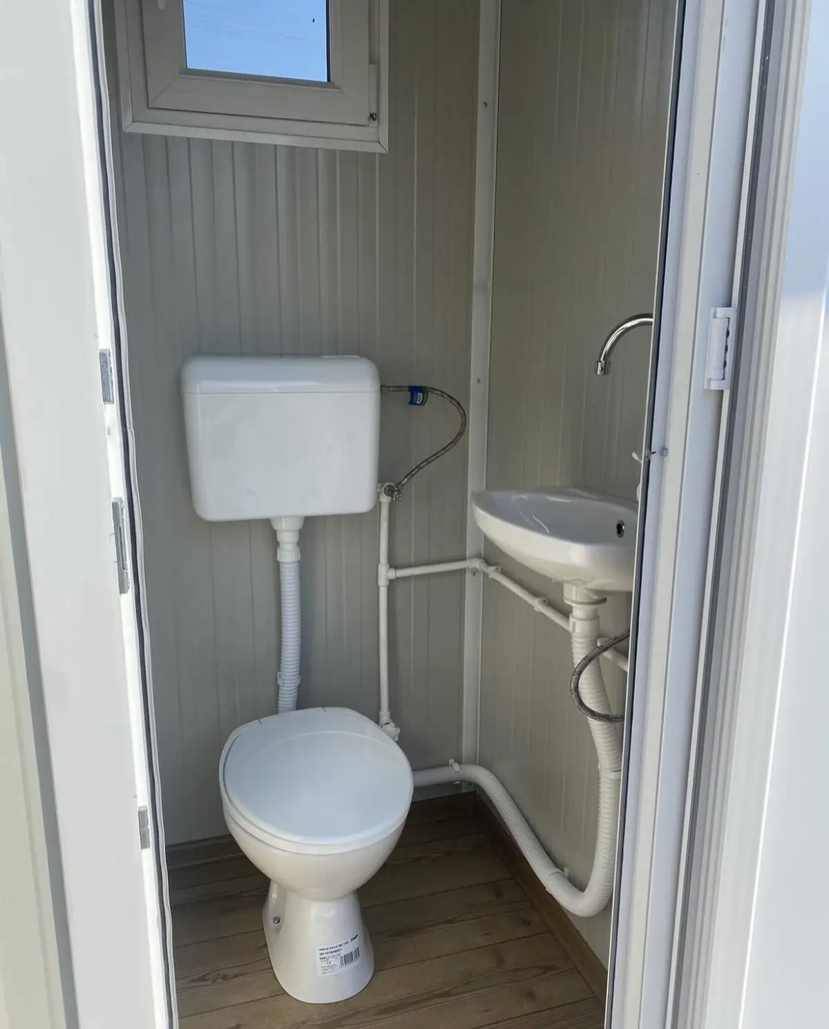 Inside a luxury restroom cabin with a flush toilet and a small sink