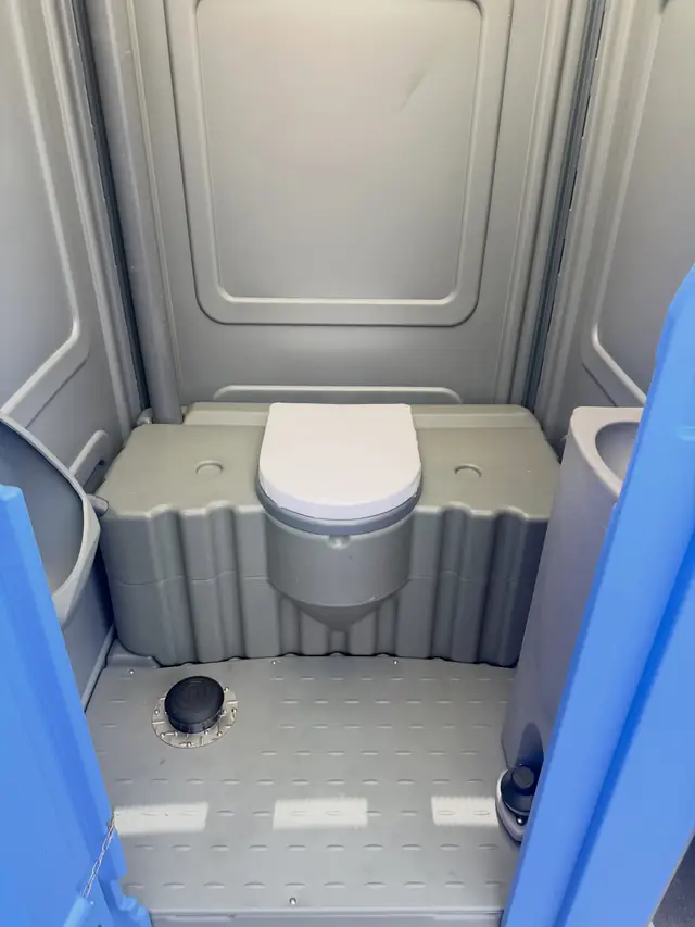 Roomy porta potty interior with a low seat and open floor