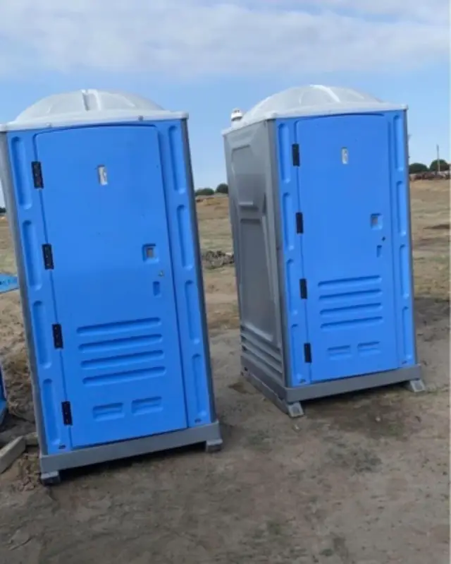 Two blue standard porta potties on a jobsite